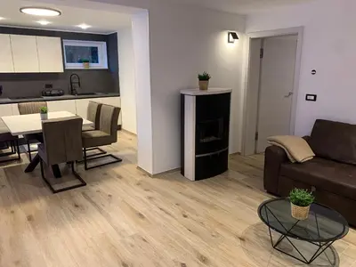 a living room with a couch and a table and a kitchen at Pine Tree Holiday House in Gozd Martuljek