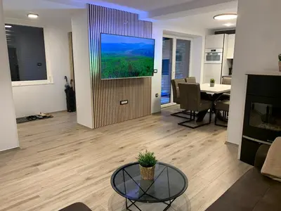 a living room with a television on a wall at Pine Tree Holiday House in Gozd Martuljek