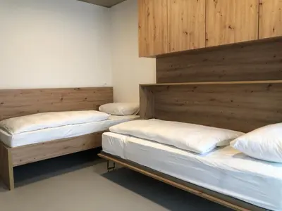 three beds in a room with wooden walls at Holiday House Šmuc in Kranjska Gora