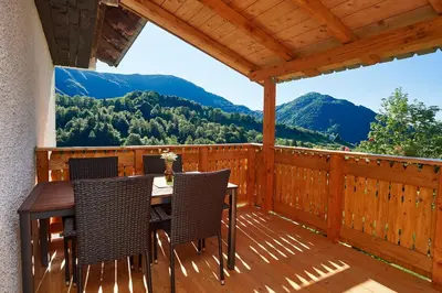 a wooden deck with a table and chairs on it at Apartma Humar in Kobarid