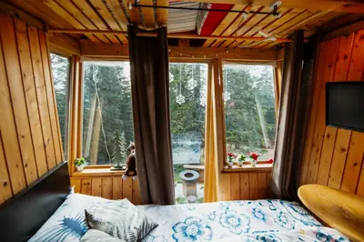 a bedroom with a bed and a large window at Tree House Alpinka Krvavec in Cerklje na Gorenjskem