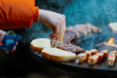 a person is cooking food on a grill at Tree House Alpinka Krvavec in Cerklje na Gorenjskem
