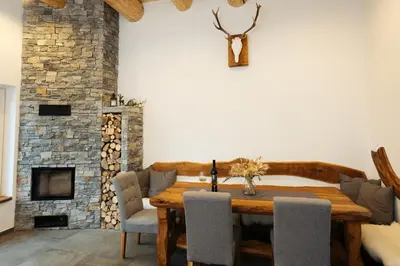 a dining room with a wooden table and a fireplace at Alpine Cottage Golica in Jesenice