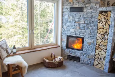 a living room with a fireplace and a window at Alpine Cottage Golica in Jesenice