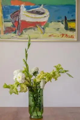 a vase with flowers in front of a painting at Private green getaway in Bled