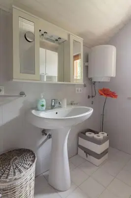 a white bathroom with a sink and a mirror at Private green getaway in Bled