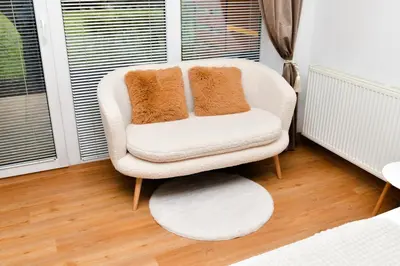 a white chair with two pillows on it in a room at Miadora apartments - Apartma Idina in Moravske Toplice