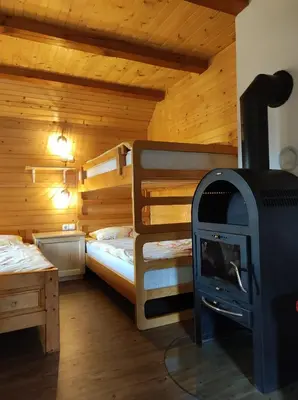 a room with two bunk beds and a wood stove at Apartma Hodnik Bohinj Uskovnica in Srednja Vas v Bohinju
