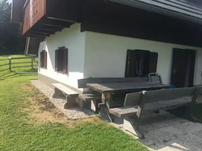a picnic table and two benches in front of a building at Apartma Hodnik Bohinj Uskovnica in Srednja Vas v Bohinju