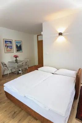a bedroom with a large white bed and a table at Apartments Katrca Bežigrad in Ljubljana