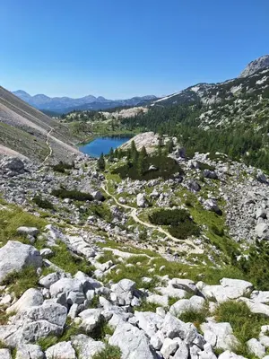 a view of a mountain lake from a rocky slope at ALPSKA ROŽA in Kranjska Gora