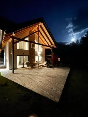 a house with a large wooden deck at night at Alpine Wooden Villa with a View in Gozd Martuljek