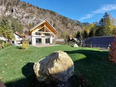 a large rock in the grass in front of a house at Alpine Wooden Villa with a View in Gozd Martuljek