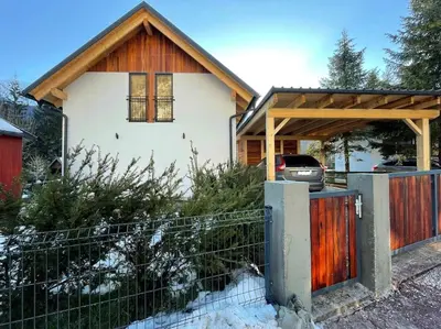 a house with a wooden gate and a fence at Alpine Wooden Villa with a View in Gozd Martuljek