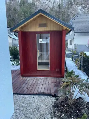 a red cabin with a glass door on a wooden deck at Alpine Wooden Villa with a View in Gozd Martuljek