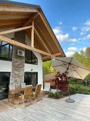 a patio with a table and chairs and an umbrella at Alpine Wooden Villa with a View in Gozd Martuljek
