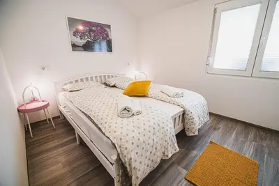 a white bedroom with a bed and a window at Gotar Apartment with Garden in Kobarid