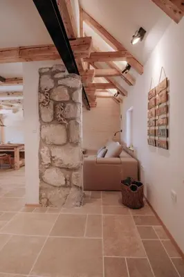a living room with a couch and a stone wall at Lovely Cottage in a mountain wilderness of the National Park in Srednja Vas v Bohinju