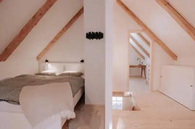 an attic bedroom with a bed and a hallway at Lovely Cottage in a mountain wilderness of the National Park in Srednja Vas v Bohinju