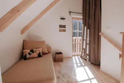 a living room with a couch in the attic at Lovely Cottage in a mountain wilderness of the National Park in Srednja Vas v Bohinju