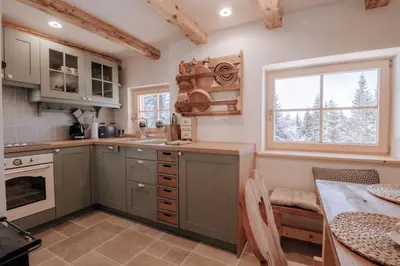 a kitchen with green cabinets and a table and a window at Lovely Cottage in a mountain wilderness of the National Park in Srednja Vas v Bohinju