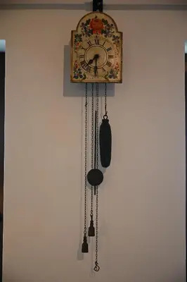 a clock is hanging on a wall with chains at SLO-ETNO HOUSE GOSTECE-Vintage Apartma in Mozirje