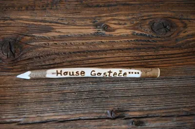 a wooden table with a bottle of house gasteide on it at SLO-ETNO HOUSE GOSTECE-Vintage Apartma in Mozirje