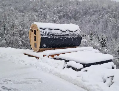 a wooden cabin covered in snow in a forest at Resort TimAJA - pool, massage pool, sauna in Trebnje