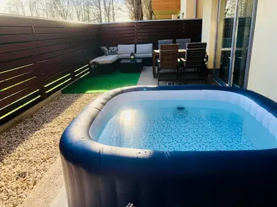 a jacuzzi tub on a patio with a table at Jenny Apartment with Jacuzzi in Brezovica