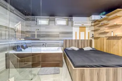 a bedroom with a bed and a tub and a sink at Private Wellness Apartment in Trebnje