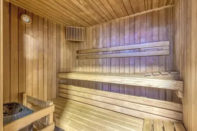 a wooden sauna with wooden shelves and a clock at Private Wellness Apartment in Trebnje