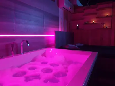 a pink bathroom with a tub with pink lights at Private Wellness Apartment in Trebnje