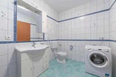 a bathroom with a toilet sink and a washing machine at Apartma Ana in Preserje