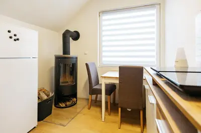 a kitchen with a wood stove and a table and chairs at Mojstranka in Mojstrana