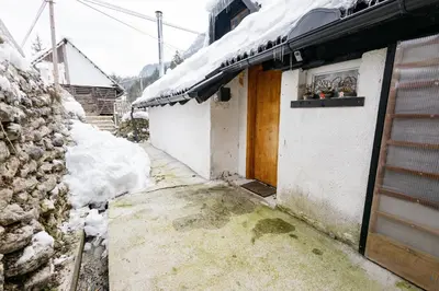 a building with a door and snow on the ground at Mojstranka in Mojstrana