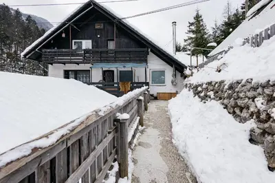 a house covered in snow next to a fence at Mojstranka in Mojstrana
