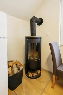 a fireplace in the corner of a room with a chair at Mojstranka in Mojstrana