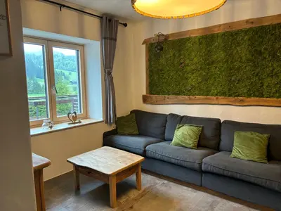 a living room with a blue couch and a table at Hiša Pod gorami II****-house with wellness in Kranjska Gora