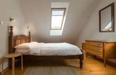 a bedroom with a bed and a dresser and a window at House Jelenko in Bovec