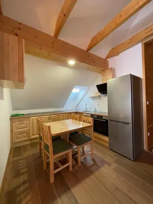 a kitchen with a wooden table and a refrigerator at Apartma LD Puščava in Lovrenc na Pohorju