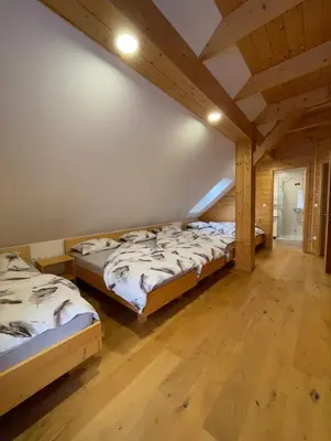 two beds in a room with wooden floors at Apartma LD Puščava in Lovrenc na Pohorju