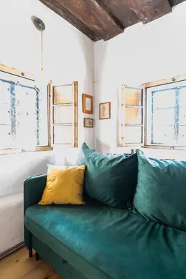 a green couch in a room with two windows at Hiša Borov Gaj in Mojstrana