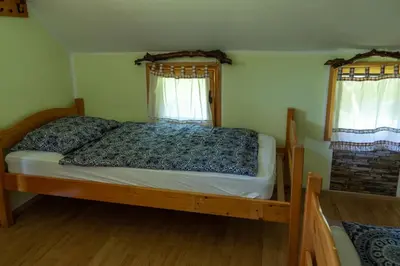 a bedroom with a wooden bed with two windows at Camping Silva in Ljutomer
