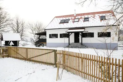 a white house with a fence in the snow at Maribor Luxury Country House Volicina 5* in Spodnja Voličina