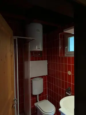 a red tiled bathroom with a toilet and a sink at Apartma Tisa in Zreče