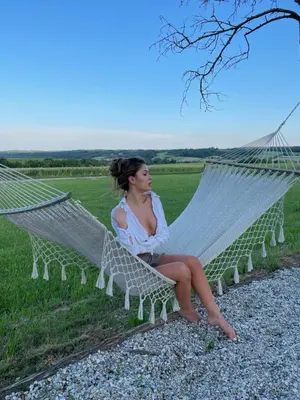 a woman sitting on a hammock in a field at Villa Goričko in Šalovci