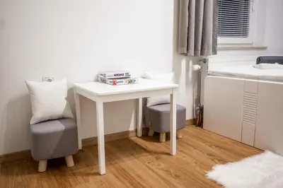 a small white table and a chair in a room at Apartma Tia 2 in Zreče