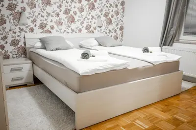 two beds in a bedroom with white sheets at Apartma Tia 2 in Zreče