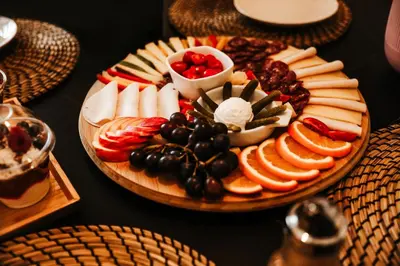 a plate of cheese and fruit on a table at Holiday House Sunset Spa in Šentjernej