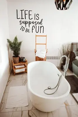 a bath tub in a bathroom with a sign that reads life is supposed to be at Holiday House Sunset Spa in Šentjernej